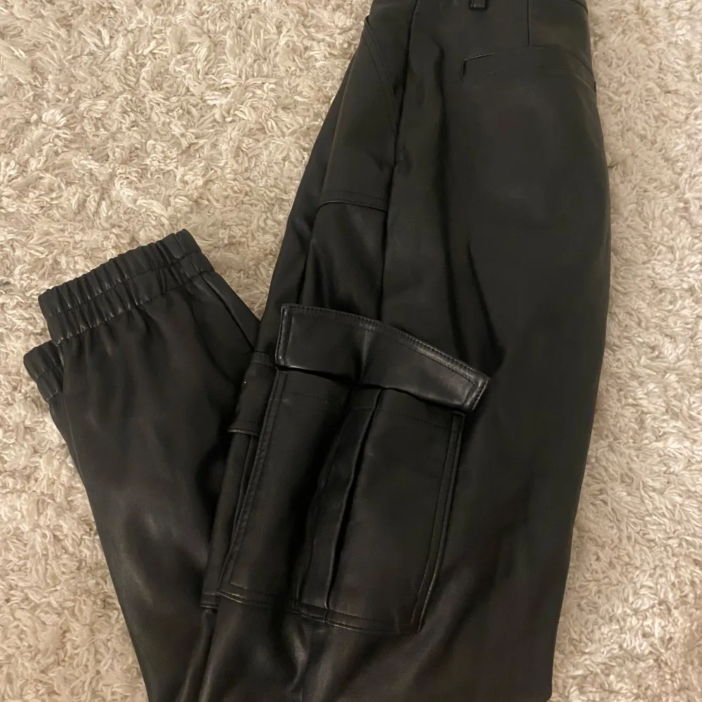 Snygga svarta cargobyxor från FB Sister i storlek XS. Byxorna har en cool design med stora fickor på sidorna och elastisk midja för extra komfort. Perfekta för en trendig look!. Farkut & Housut.