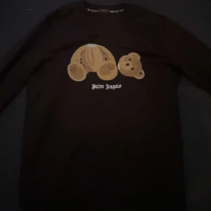 Svart långärmad tröja från Palm Angels - Säljer en svart långärmad tröja från Palm Angels med ett unikt nallemotiv på framsidan. Tröjan har en klassisk passform och är perfekt för en stilren look. Passar bra till både jeans och chinos.