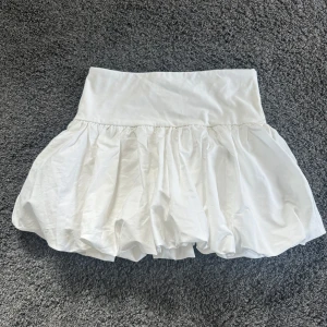 Vit ballongkjol från Gina Tricot - Säljer en söt vit ballongkjol från Gina Tricot. Kjolen har en elastisk midja och en fluffig design som ger en lekfull look. Perfekt för att skapa en trendig outfit. 🩶