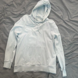 Ljusblå hoodie från Colorful Standard storlek Small - Säljer en stilren ljusblå hoodie från Colorful Standard, tillverkad i ekologisk bomull. Den har en klassisk känguruficka och justerbar huva med dragsko. Perfekt för en avslappnad stil. Köpte den i Köpenhamn har knappt använd den. Har otroligt bra kvalité man märker de på hoodien väldigt skön. Storlek Small 
