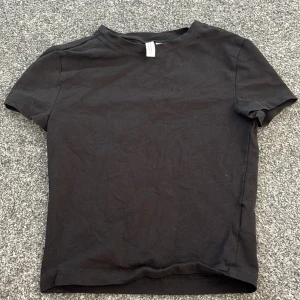 Svart t-shirt från H&M Divided - Säljer en enkel och stilren svart t-shirt från H&M Divided. Perfekt basplagg med korta ärmar och rund hals. Gjord i mjukt bomullsmaterial för en bekväm passform. Passar till allt! 🖤