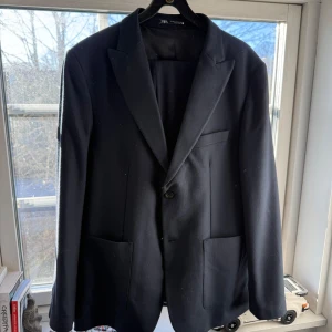 Mörkblå kostym - Elegant mörkblå kostym med byxor från Zara med klassisk design. Kostymen har en enkelknäppning och två framfickor. Aldrig använd 