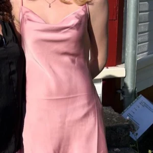Rosa klänning från Stradivarius - Säljer en elegant rosa klänning från Stradivarius. Klänningen har smala axelband och en mjuk, glansig yta som ger en lyxig känsla. Perfekt för speciella tillfällen. 💖(använd 1 gång)