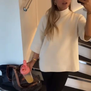 Vit polotröja - Säljer en stilren vit polotröja med trekvartsärm. Perfekt för en minimalistisk look. Tröjan har en lös passform och är gjord i ett mjukt material. Har ett litet slitage i ärmen Pgd att tråden va uppe när jag fick den