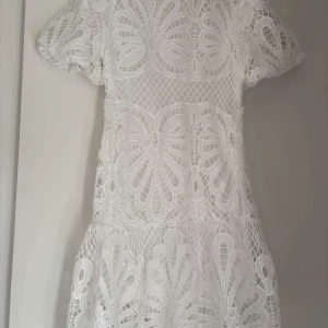 Vit spetsklänning - Säljer en vit spetsklänning med korta ärmar. Perfekt för sommarens alla tillfällen. Perfekt till studenten. Köptes på plick så vet ej märket tyvärr. Skriv vid fler frågor💗