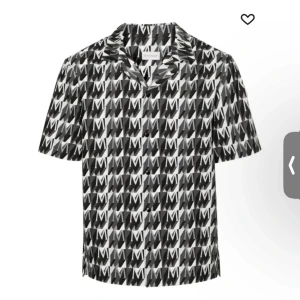 Svartvit skjorta med monogram från Moncler - Snygg skjorta från Moncler med ett iögonfallande svartvitt monogrammönster. Skjortan har korta ärmar och knappar framtill, perfekt för en stilren look.