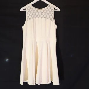 Vit ärmlös klänning  - Snygg vit klänning med ett prickigt mönster på övre delen. Den är ärmlös och har en dragkedja i sidan samt knapp i nacken. Perfekt för sommarens alla tillfällen!