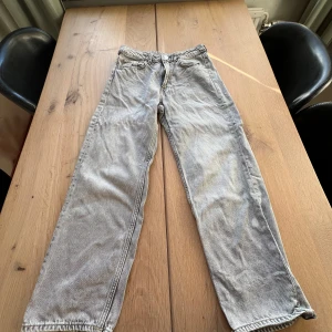Grå jeansbyxor - Snygga grå jeansbyxor med en klassisk straight fit. Byxorna har en traditionell femficksdesign och är perfekta för en avslappnad stil. De är tillverkade i ett slitstarkt material som ger en skön känsla.