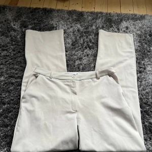 Beige byxor från 157 - Snygga beige byxor från 157 i storlek M. De har en klassisk design med raka ben och en knapp framtill. Perfekta för en stilren look.