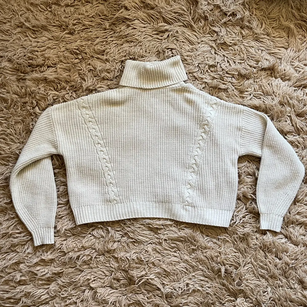 Beige stickad polotröja med kabelstickade detaljer. I fint skick.. Neuletakit & Villapaidat.