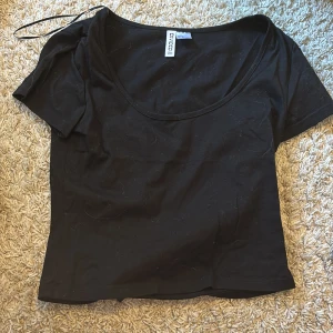 Svart top från H&M - Säljer en svart topp från HM. Den har korta ärmar och en rundad halsringning. Perfekt för en enkel och snygg look. 