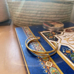 Guldarmband med tvinnad design - Elegant guldarmband med en stilren tvinnad design. Perfekt för att ge en touch av lyx till din outfit. Armbandet är öppet och justerbart för att passa de flesta handleder. Endast testat men aldrig använd. Beställde armbandet från Cille Juveler och det är i bra kvalite och är skapat av rostfritt stål ⚜️           Det tillkommer en liten smyckes-låda, nypriset var 300 kr. 