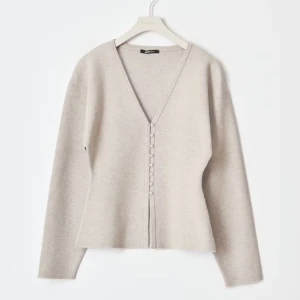 Beige kofta från ginatricot  - Säljer en stilren beige kofta från Ginatricot med v-ringning och knappar framtill. Koftan har långa ärmar och är perfekt för lager-på-lager under kyligare dagar. Passar både till jeans och kjol för en avslappnad look. Ny utan prislapp 