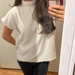 Trekvartsärmad polotröja - Säljer en stilren vit polotröja med korta ärmar. Perfekt för en avslappnad men ändå chic look. Tröjan har en hög krage som ger extra värme och stil. Köpt i Italien och aldrig använd 