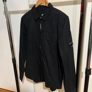 CP Company - Helt ny och oanvänd CP company overshirt, 10/10 skick. Den är lite skrynklig pga en flytt. Men det är inga skador eller liknande på den. Det är storlek L och den sitter som en L, men passar även M. Hör av er vid frågor!