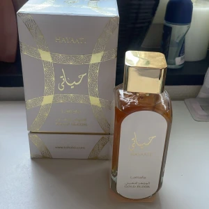 Lattafa Hayaati Gold Elixir edp - Elegant parfymflaska med guldlock och vit etikett. Förpackningen är vit med gyllene detaljer och arabiska inskriptioner. En skön ladder och söt doft som funkar prefekt för våren och hösten. Ca95ml kvar.