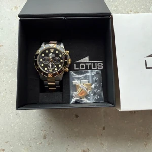 💸Lotus klocka i silver och guld💸 - Snygg Lotus kronografklocka med en kombination av silver och guld på armbandet. Urtavlan är svart med guldiga detaljer och flera sub-dials. Perfekt för den som gillar en stilren och elegant look. Skriv för fler frågor och funderingar!