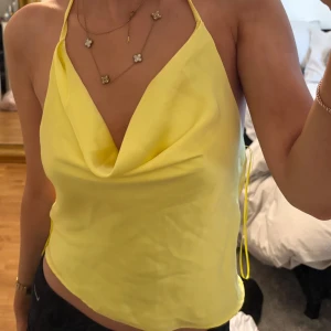 Gul halterneck topp - Säljer en snygg gul halterneck topp med öppen rygg och draperad framsida. Perfekt för sommarens varma dagar. Toppen är i ett lätt och luftigt material som ger en skön känsla. Passar perfekt till både jeans och kjol. 🌼