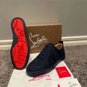 Svarta sneakers från Christian Louboutin - Snygga svarta sneakers från Christian Louboutin med den ikoniska röda sulan. Skorna har en stilren design med snörning och är tillverkade i mocka. Perfekta för den som vill ha en touch av lyx i vardagen.