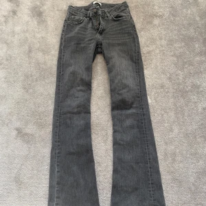 Grå bootcut jeans - Snygga grå bootcut jeans med låg midja och klassisk femficksdesign. Jeansen har en lätt slitning vid fållen för en avslappnad look. Perfekta för en trendig stil.