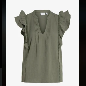 Olivgrön blus från Vila - Säljer en olivgrön blus från Vila med volangdetaljer på ärmarna och en v-ringad hals, perfekt för en stilren look. Aldrig använd och har prislappen kvar!
