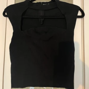 Fest topp  - Snygg svart ärmlös topp med cool cut out-detalj vid halsen och croppad passform. Perfekt för att lyfta din outfit med en edgy vibe. Stängs med dragkedja bak. Helt ny men finns ingen lapp