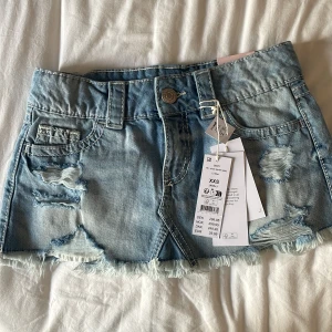 Slutsåld jeanskjol från Gina Tricot - Supersnygg ljusblå jeanskjol med låg midja från Gina Tricot som är slutsåld.Kjolen har slitna detaljer, fransig nederkant och klassiska fickor både fram och bak. Den är lågmidjad och passar till allt. Den är endast testad och prislappen sitter kvar. Skulle säga att den passar mer som en XS. 