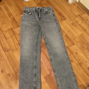 Grå raka jeans från Zara, strl 34 - Säljer ett par grå jeans från Zara i storlek 34. Jeansen har rak passform och slits nere , klassisk femficksdesign och normal midja. Materialet är denim i bomull och färgen är snyggt tvättad grå. Perfekta till sneakers eller boots. 