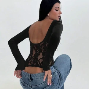 Svart topp med spets och öppen rygg - Priset kan diskuteras vid snabb affär!!💕💕 Svart långärmad topp med tight passform och  öppen rygg. Baksidan har  spets med blommigt mönster som ger en snygg kontrast mot de släta ärmarna och framsidan. Perfekt för dig som vill sticka ut med en unik detalj. 