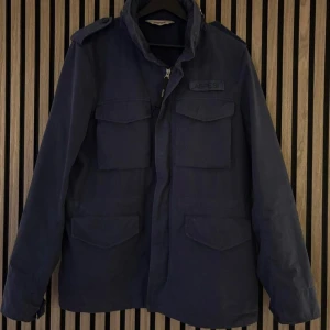 ASPESI M65  - Jacka i M65 utförande från Italienska Aspesi. Denna är tillverkad i bomull som sedan stentvättats för att få en mer vintagekaraktär. Dold luva i kragen + Badge som kan bytas ut (kardborre).   Storlek L  Blå   Köpt från Ströms förra sommaren (2024) för  7,999kr och endast använd en handfull gånger sedan dess. Slutsåld på hemsidan just nu i de   större storlekarna.  Digitalt kvitto+ samtliga tillbehör som följde med finns kvar (tags, extra badge, knappar och galge).  PM för frågor eller fler bilde