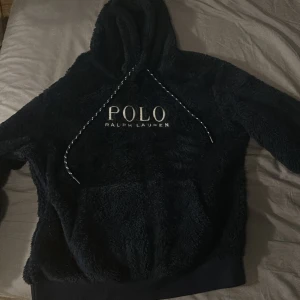 Svart fleece hoodie Polo Ralph Lauren - ALDRIG ANVÄND! Mysig svart hoodie från Polo Ralph Lauren i fluffig fleece med stor broderad logga på bröstet. Tröjan har huva med snörning och en stor magficka. Perfekt för kalla dagar när du vill vara både bekväm och snygg.