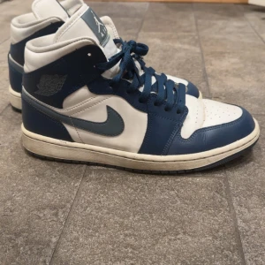Nike Air Jordan 1 High blå/vit - Säljer ett par Nike Air Jordan 1 High sneakers i blått och vitt skinn. I storlek 40,5 och inte speciellt använda. Det finns några tecken på användning som inte är speciellt stora som kan visas vid önskemål.