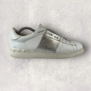 Valentino Garavani sneakers  - Säljer dessa snygga Valentino Garavani sneakers i vitt skinn med metallic-silver detalj på sidan och ikoniska nitar vid hälen. Skriv vid funderingar eller frågor! Pris kan diskuteras!