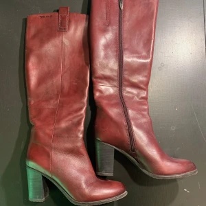 Vinröda skinnstövlar från Tamaris - Snygga vinröda stövlar från Tamaris (jag tror det är äkta skinn) med rund tå och hög klack. Dragkedja på insidan för enkel påtagning. Har inga defekter.