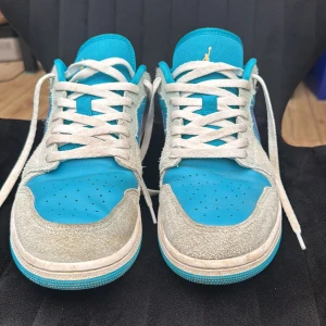 Nike Air Jordan 1 Low Turkos/Lila - Nike Air Jordan 1 Low med turkosblå mesh och skinn, grå mockadetaljer och lila swoosh. Klassisk Jordan-logga broderad bak, vita snören och platt sula. Perfekt för dig som vill sticka ut med färg och stil. Pris går o diskutera 