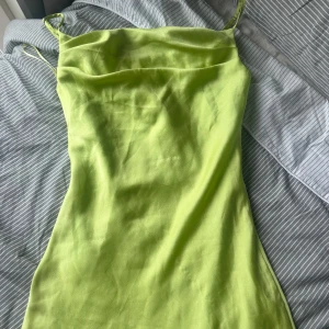 Ljusgrön långklänning från Koton - Säljer en snygg ljusgrön långklänning från Koton med tunna axelband och slinky passform. Klänningen har en stilren, minimalistisk look och är tillverkad i ett glansigt, mjukt material som känns lyxigt mot huden. Perfekt för dig som vill sticka ut med färg!