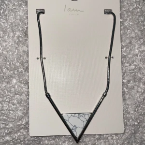 Halsband  - Snyggt halsband med en silverfärgad kedja och ett stort triangelformat hänge i vit marmorlook med gråa ådror. Modern och stilren design som verkligen sticker ut. Perfekt accessoar för att lyfta din outfit. OANVÄND