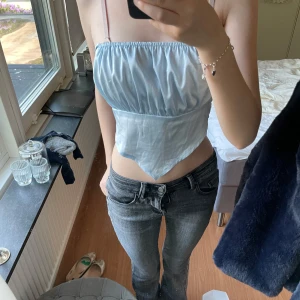 Ljusblå satin tubtopp med knyt💗 - Supersöt ljusblå tubtopp i satin och knyt i ryggen. Toppen har en snygg omlott-look framtill med spetsig nederkant och smockad rygg för extra passform. Perfekt till jeans eller kjol för en trendig look, jätte fin till sommaren!!