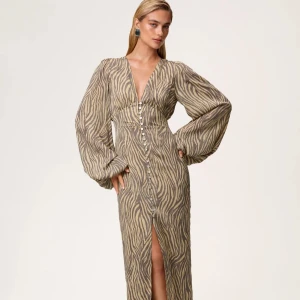 Adoore positano dress - Snygg adoore klänning med zebramönster i beige och brunt. Djup v-ringning, långa puffärmar och knappar framtill hela vägen ner till en slits. Klänningen är endast använd 2 gånger men har inga synliga defekter. 