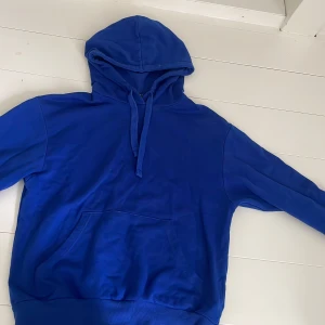 Blå hoodie från Monki  - En klassisk blå hoodie från Monki i storlek XXS. Tröjan har huva med snörning, stor ficka framtill och långa ärmar.