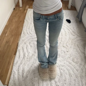 Ljusblå bootcut jeans med låg midja - Säljer ett par ljusblå bootcut jeans med låg midja och klassisk femficksdesign. Sydda för att vara mer low waist! Lite nertrampade längst ner!