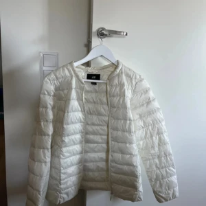 Vit tunn dunjacka - En vit tunn dunjacka i strl S/M från H&M. Mycket bra skick förutom ett hål på ärmen jag satt en tejp bit över. (Se bild 4) Syns knappt!