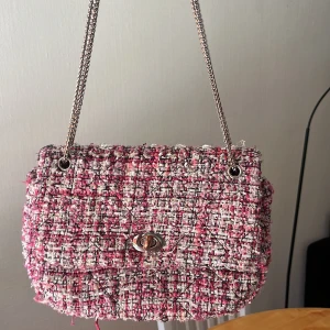 Rutig axelväska från Becksöndergaard - Säljer en superfin axelväska från Becksöndergaard i rutigt bouclétyg med rosa, beige och svarta toner samt inslag av guldtråd. Väskan har används mycket och är lite sliten men är fortfarande jättefin ändå!!💕