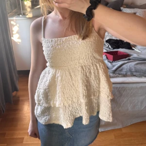 Volang top från Gina Tricot - En söt volang top från Gina tricot i storlek S. Sitter tightare över bysten, har två axelband och två volanger. Super fin till kjol och byxor. Jag säljer den då jag tycker att den är lite för stor över bysten på mig. Hör av dig vid frågor💗☺️