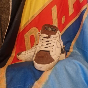 Phillipe modell - Snygga sneakers i vitt med vinröda detaljer och inslag av mörkblått. Ovandelen har partier i mocka och skinn, med klassisk snörning och platt sula. Perfekta för dig som vill ha en stilren men ändå färgstark look. Stl 41