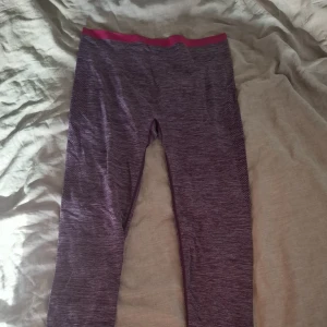 Lila leggings med rosa midja XS/S - Säljer ett par snygga lila leggings med melerad look och rosa resår i midjan. De har diskreta meshdetaljer längs benen för extra stil och andningsförmåga. Perfekta för träning eller chill. Supersköna och stretchiga!