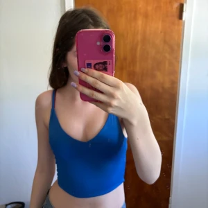 Blå croppad linnetopp från Amisu - Snygg blå croppad linnetopp från Amisu med smala axelband och v-ringning. Perfekt för varma dagar eller lager på lager. Toppens material är mjukt och stretchigt, vilket gör den superbekväm att bära. Enkel och stilren design som är lätt att matcha.