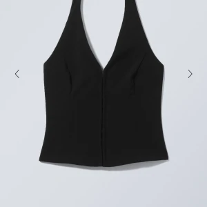 Svart korsett-topp med djup v-ringning - Snygg svart korsett-topp med djup v-ringning och halterneck. Toppen har krokar framtill för stängning och en figurnära passform som framhäver siluetten. Perfekt för dig som vill ha en stilren och edgy look. Skriv privat för mer bilder. Helt ny ej använd