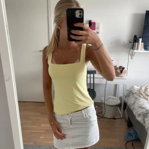 Ljusgul linnetopp med breda axelband - Supersöt ljusgul linnetopp med breda axelband och fyrkantig ringning. Toppen är figurnära och perfekt för varma dagar. Enkel och stilren design som är lätt att matcha med både kjol och jeans.