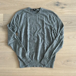 Grå merinoulltröja från Uniqlo XS - Säljer en stilren grå långärmad tröja från Uniqlo i mjuk merinoull. Tröjan har rund halsringning, ribbade muddar och en klassisk passform. Perfekt att slänga på sig när det är lite kyligare ute.